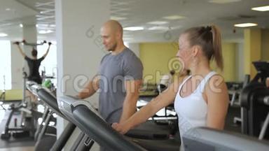 在跑步<strong>机</strong>上，男人和女人开始在健身房的跑步<strong>机</strong>上跑步。