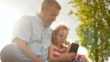 祖父和孙女看智能<strong>手机</strong>。 可爱的女孩和成熟的男人<strong>玩手机</strong>