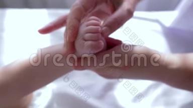 足部按摩，治疗师用手缓慢按摩婴儿特写的小腿