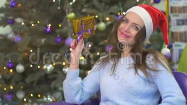 圣诞老人的帽子里有一个美丽`深色头发的女人，用金色的包装展示节日礼物