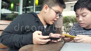慢动作4K快乐的亚洲男孩一起在智能<strong>手机</strong>上在线<strong>玩手机</strong>游戏。 有福的男孩和朋友商量策略