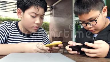 慢动作4K快乐的亚洲男孩一起在智能手机上在线玩手机游戏。 有福的男孩和朋友<strong>商量</strong>策略