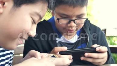 慢动作4K快乐的亚洲男孩一起在智能手机上在线玩手机游戏。 有福的男孩和朋友商量策略