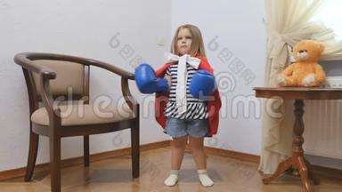 可爱的小女孩戴着拳击手套，穿着红色斗篷，展示了她作为超级英雄的力量