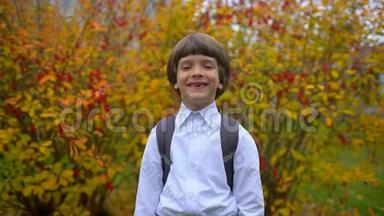 <strong>一年级</strong>学生玩得开心，带着背包在户外对着镜头笑的可爱男孩的画像
