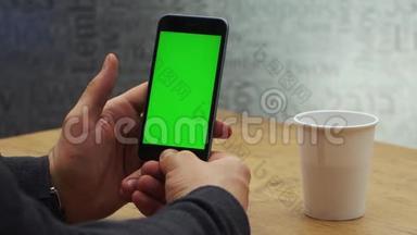 人使用垂直智能手机与绿色屏幕。 男人用手机`手的特写镜头。 铬钥匙。 关门