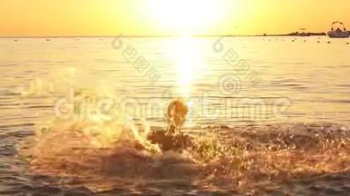 快乐男孩在海上嬉戏的剪影日落时升起水花，动作缓慢