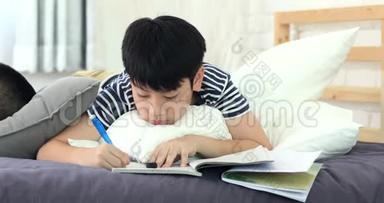 亚洲男孩在家做作业，朋友休息在床上和看书。