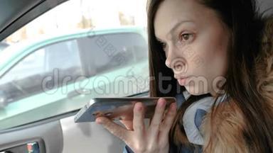 年轻漂亮的女人坐在车里的<strong>手机</strong>上说着<strong>语音</strong>信息。