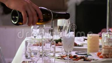 服务员把香槟酒、白起泡酒倒入玻璃杯中。 泡沫上升。 一家餐馆。