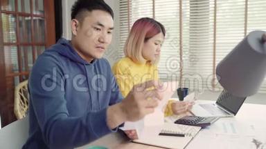 年轻时强调，亚洲夫妇管理财务，在现代家庭使用笔记本电脑和计算器审查他们的银行账户。