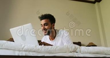 年轻人用笔记本电脑<strong>躺在床上</strong>快乐地微笑着，西班牙<strong>男人在床上</strong>聊天