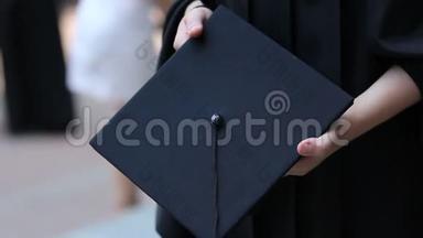 毕业学生的双手拿着学术帽，在毕业证书颁发前感到紧张