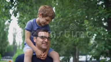 一个快乐而成年的男人把他的小儿子扛在肩上，一个男孩喜欢在男人身上度过他`暑假