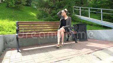 一个年轻漂亮的女孩坐在太阳底下的公园长椅上