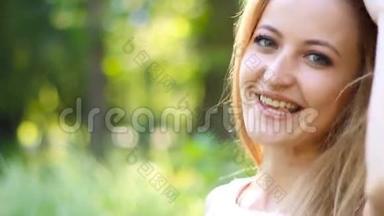 空中<strong>之吻</strong>。 微笑的金发女人在夏天公园炫耀她那长长的茂盛的头发
