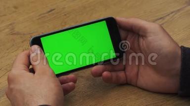 人使用水平智能手机与绿色屏幕。 男人用手机`手的特写镜头。 铬钥匙。 关门
