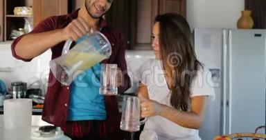 一对夫妇在酒杯里倒入<strong>鲜榨果汁</strong>，男人和女人在厨房里一起谈幸福的微笑