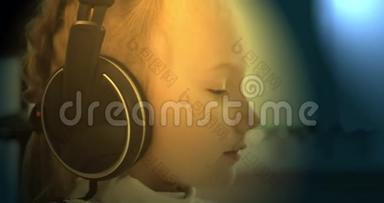 一个小女孩在耳机上听音乐。