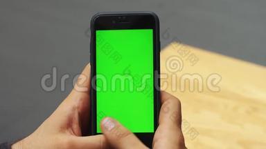 人使用垂直智能手机与绿色屏幕。 男人用手机`手的特写镜头。 铬钥匙。 关门