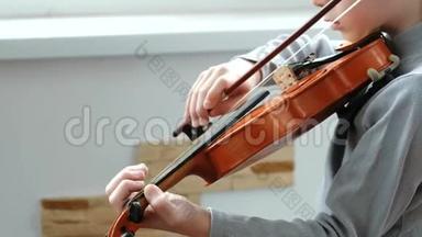 拉小提琴。 无法辨认的七岁男孩在拉小提琴特写。