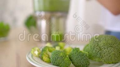 榨汁机制作绿色花椰菜蔬菜汁.. 关闭榨汁机和女人手把蔬菜放入果汁中