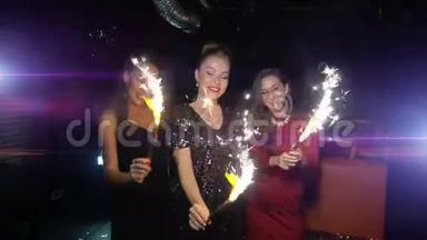 三个女人跳舞，玩得开心，在新年或圣诞晚会上捧<strong>起火</strong>花