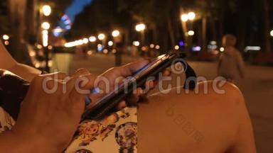晚上公园，一个女孩在手机进入社交网络。 特写镜头。