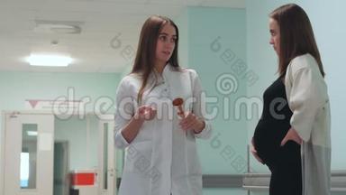 一位孕妇走在移植中心的走廊里，与穿着白色晨衣的医生交流