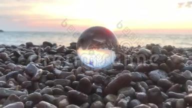 美丽的夕阳<strong>倒映</strong>在石头上的水晶球里，阳光洒在水面上，沙滩上，风景如画