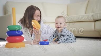 快乐的妈妈和宝宝在家里地毯上玩玩具。 侧面看一对快乐的母子玩玩具