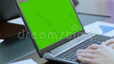 在带有绿色<strong>屏幕</strong>的笔记本电脑上工作的人，使用触摸板，<strong>滚动</strong>网页