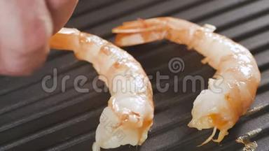 大虾在平底锅里烤。 煮熟的手放下锅里的虾。