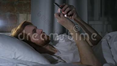 红发胡子男在床上浏览电子邮件和电话留言