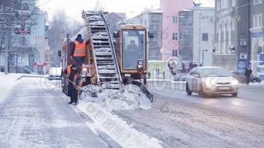 拖拉机从雪地上清理道路。 挖掘机清扫城市大量积雪的街道.. 工人清扫