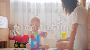 快乐的妈妈和宝宝在家里地毯上玩玩具。 侧面看一对快乐的母子玩玩具