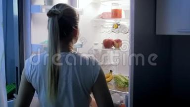 年轻美丽的女人在夜间<strong>打开冰箱</strong>，喝酸奶的慢镜头
