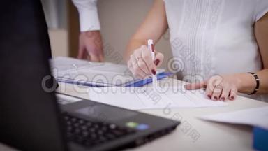 一个女人为她的老板展示了法律文件的变化，男人`手翻着纸，那位女士