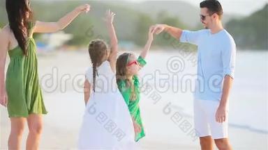 父母和可爱的两个孩子在海滩上的暑假里玩得很开心。 四口之家相爱。 开心快乐