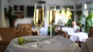 带有戒指的玻璃底部放在白色托盘上的香槟中，在<strong>浪漫</strong>的活动中没有聚焦的背景上放<strong>小花</strong>