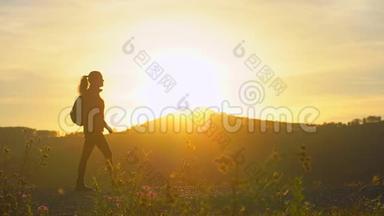 徒步旅行女游客的剪影，带着背包在日落时分在山上徒步旅行。 女旅行者女旅行者