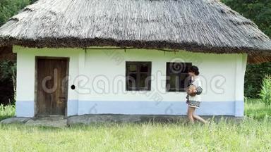 一个乌克兰女孩拿着一个<strong>水壶</strong>在<strong>小</strong>屋附近闲逛。