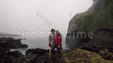 年轻的旅行夫妇穿着雨衣站在海边享受<strong>这次</strong>旅行。 游客男人和女人。