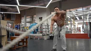 强壮的男人在健身房和战斗绳索一起工作。