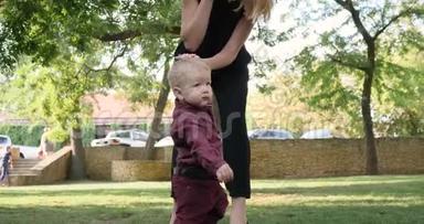 当他在公园里练习第一步时，妈妈支持她的小宝宝