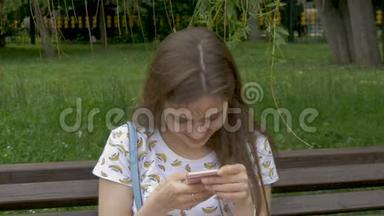 一个漂亮的白人女孩正在智能手机上读短信。我有好消息和<strong>喜事</strong>。笑，笑，心情好。