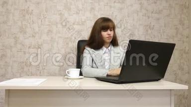 年轻的女孩在电脑办公室工作。 一位漂亮的女商人在笔记本电脑上写商务信函