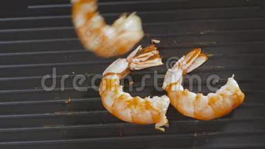大虾在平底锅里烤。 煮熟的手放下锅里的虾。