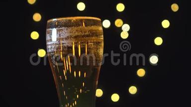 冷光啤酒在一个玻璃与水滴在哑光黑色背景与模糊的光。