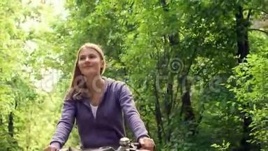 快乐的运动快乐的运动活泼的运动年轻女子骑着帽衫在夏天`阳光明媚的公园里骑自行车